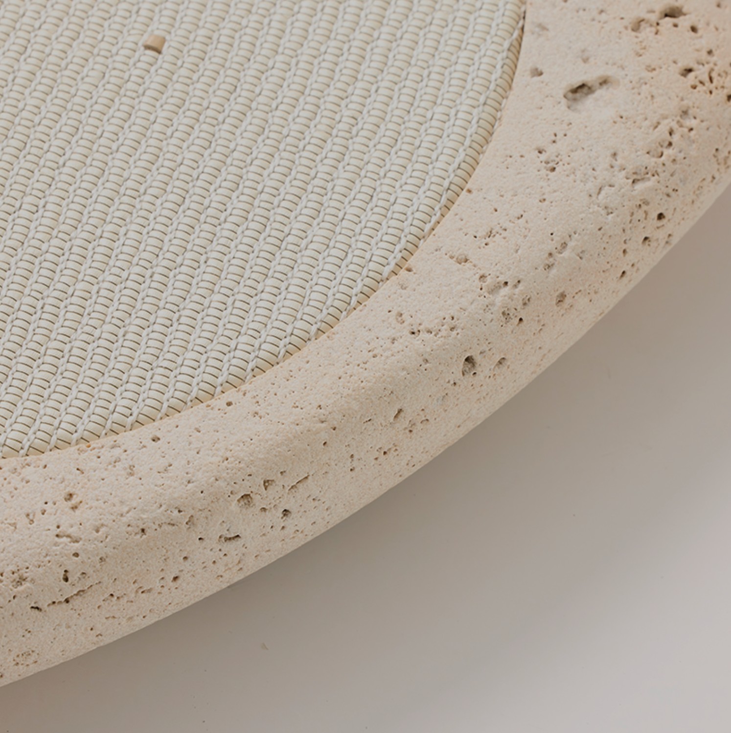 Close-up of a textured beige circular wireless phone charger  with a white woven leather centre